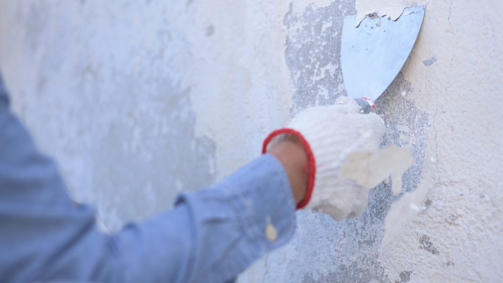 unrecognizable worker working outdoor, scraping, using trowel.