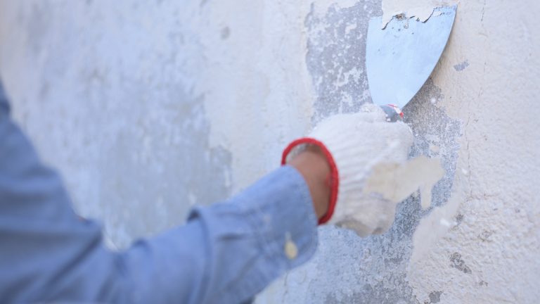 unrecognizable worker working outdoor, scraping, using trowel.